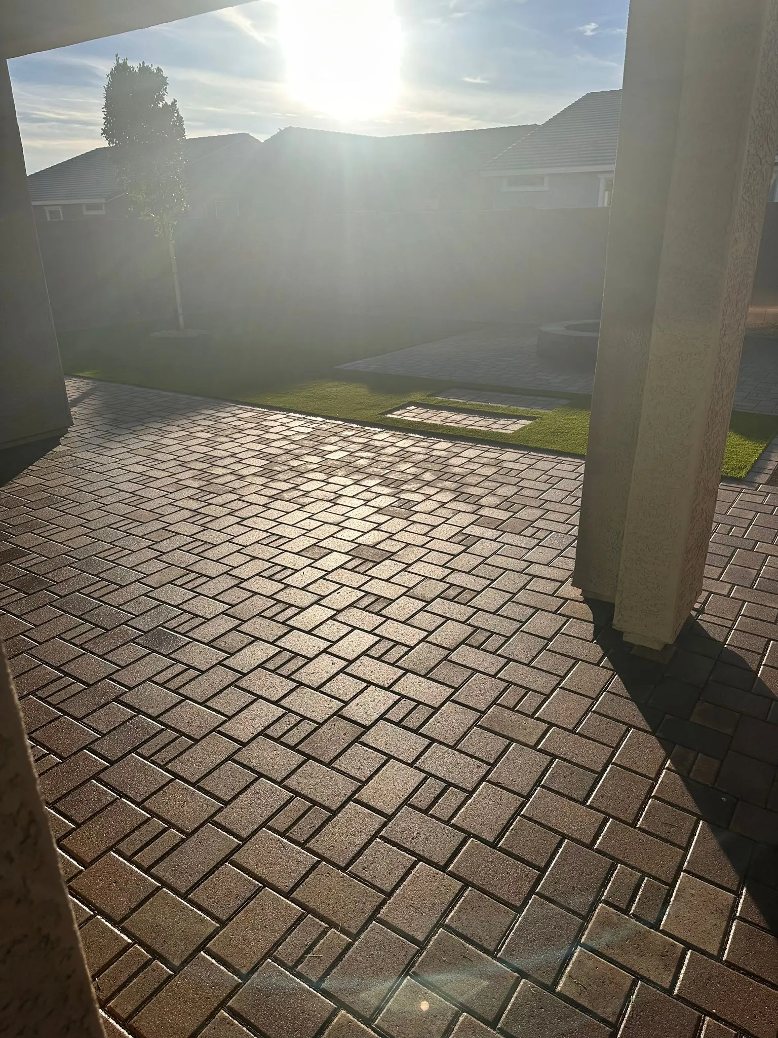 Paver patio under a covered patio with a separate fire pit pad beyond