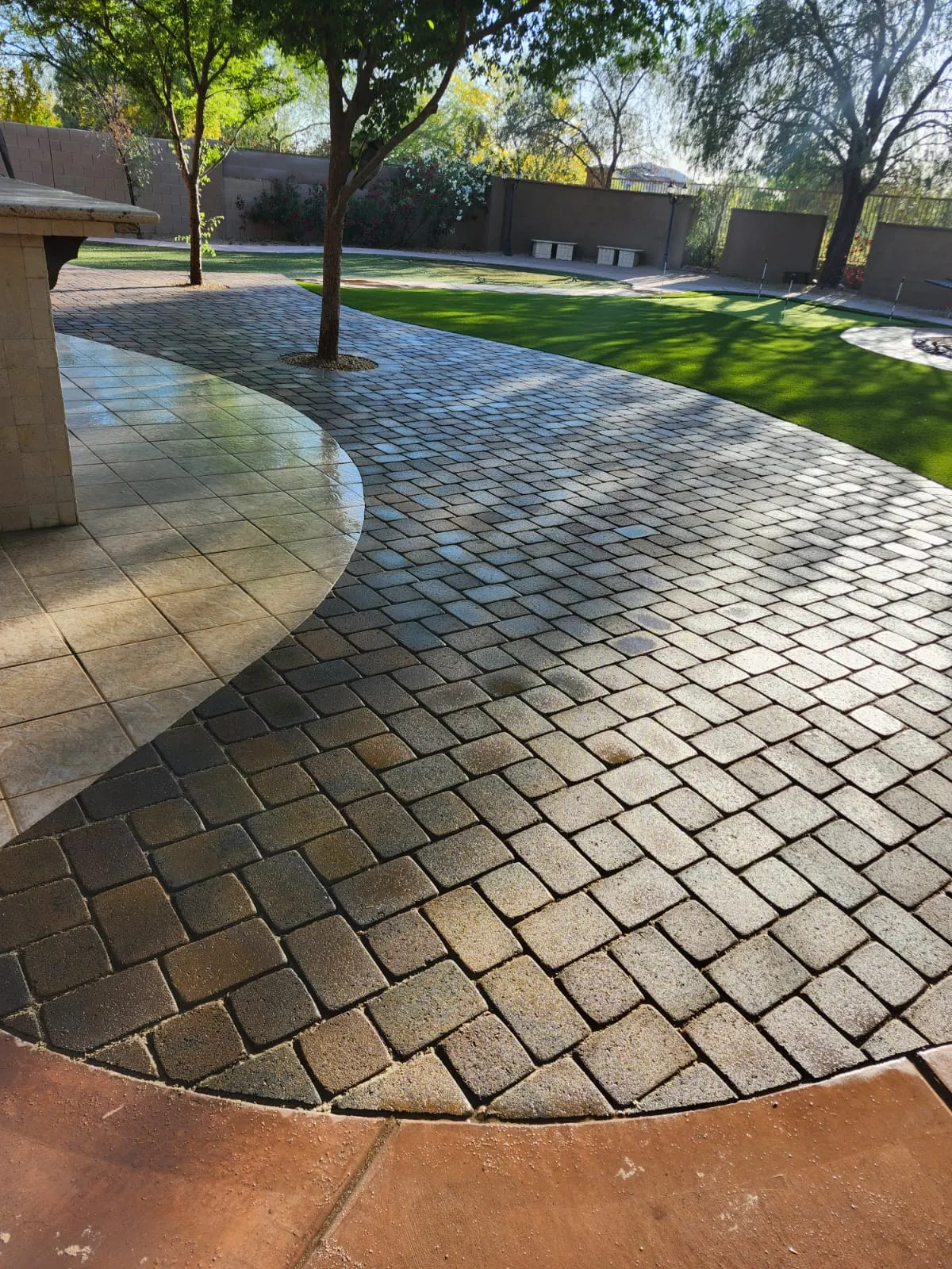Curved cobble paver patio beside a tiled outdoor bar area