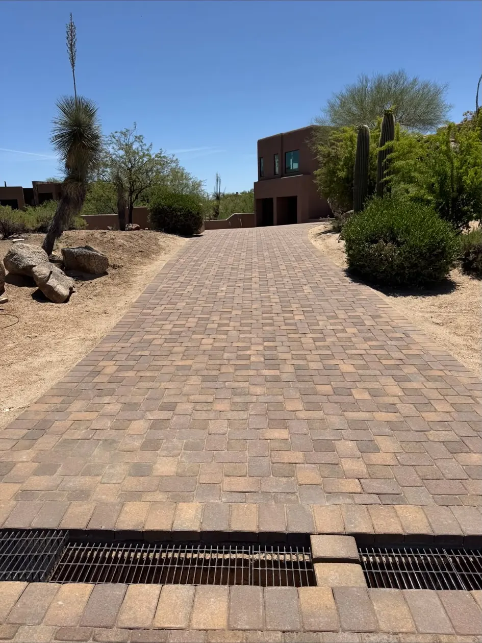 Tumbled paver driveway with trench drain on a desert lot